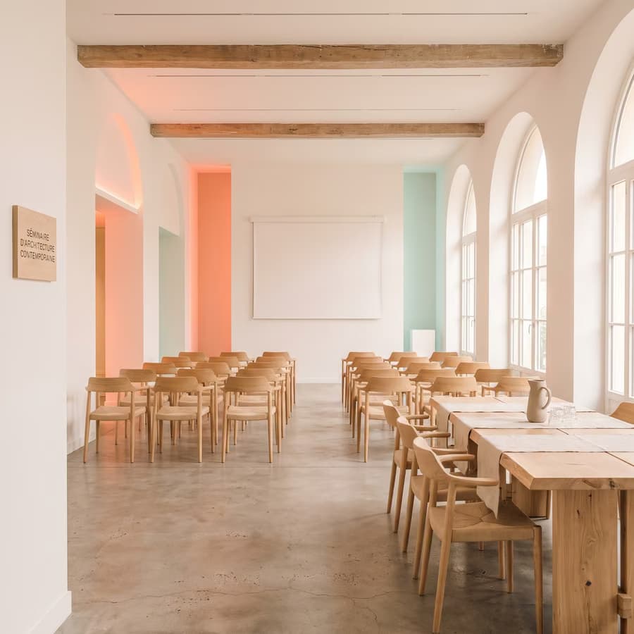 Séminaire : salle lumineuse, chaises en bois clair et tables de travail