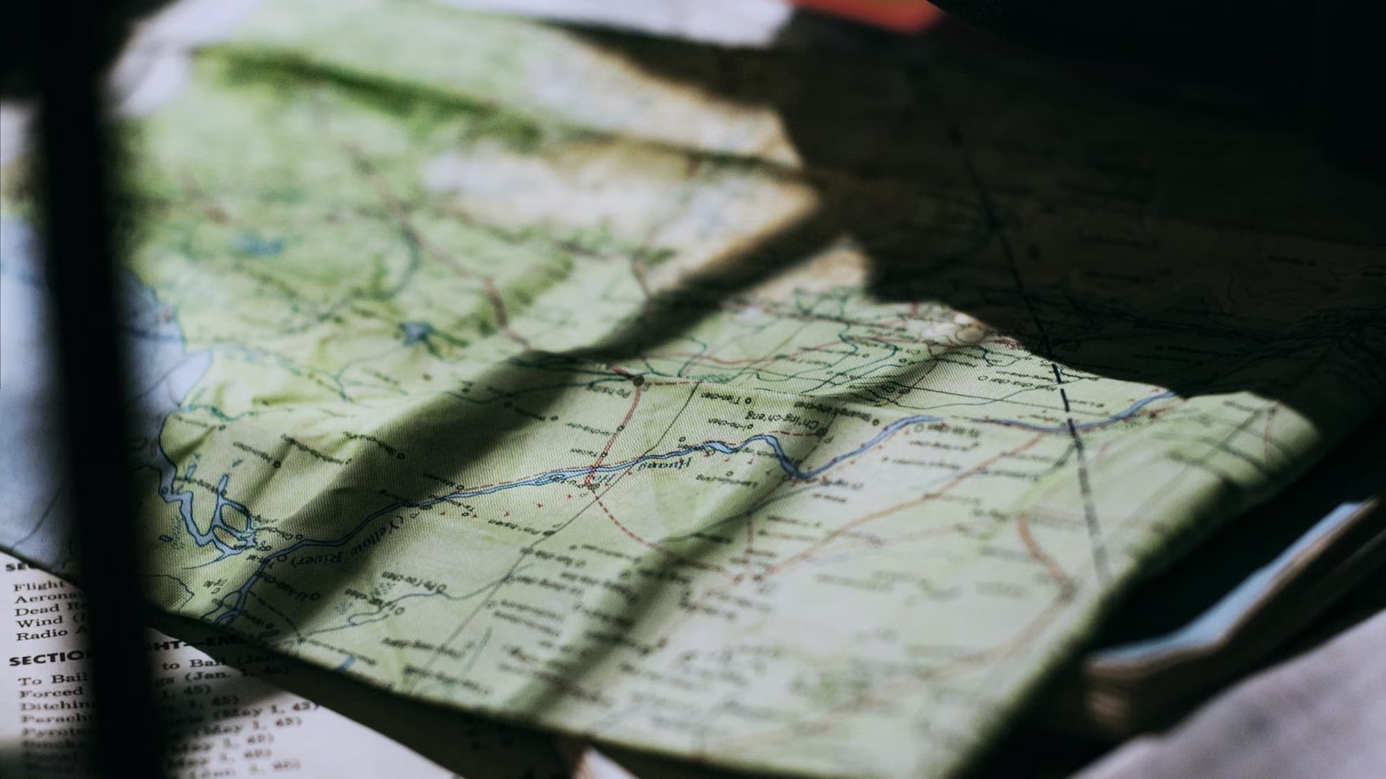 Carte routière dépliée, traversée par l’ombre d’une fenêtre