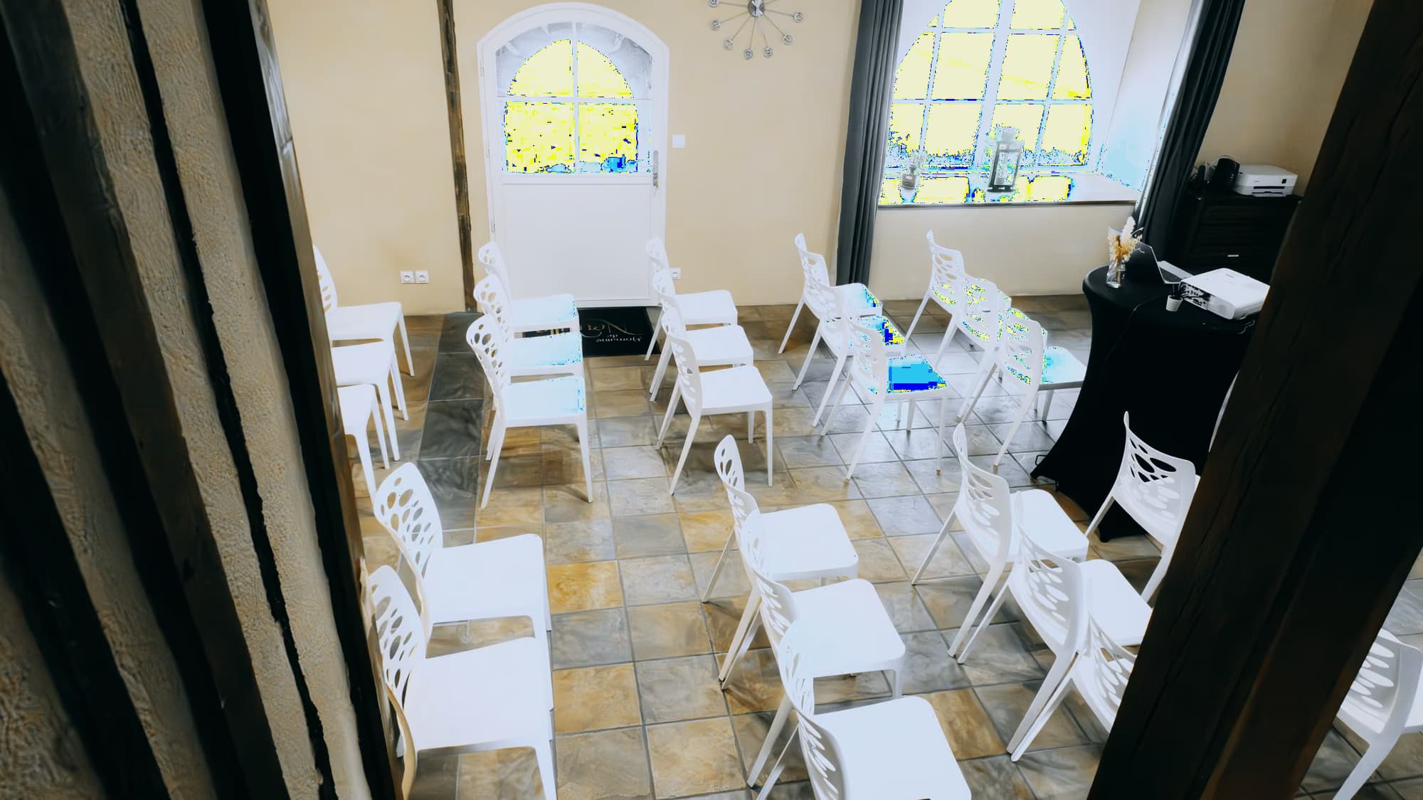 Salle municipale préparée, chaises blanches alignées sous les vitraux
