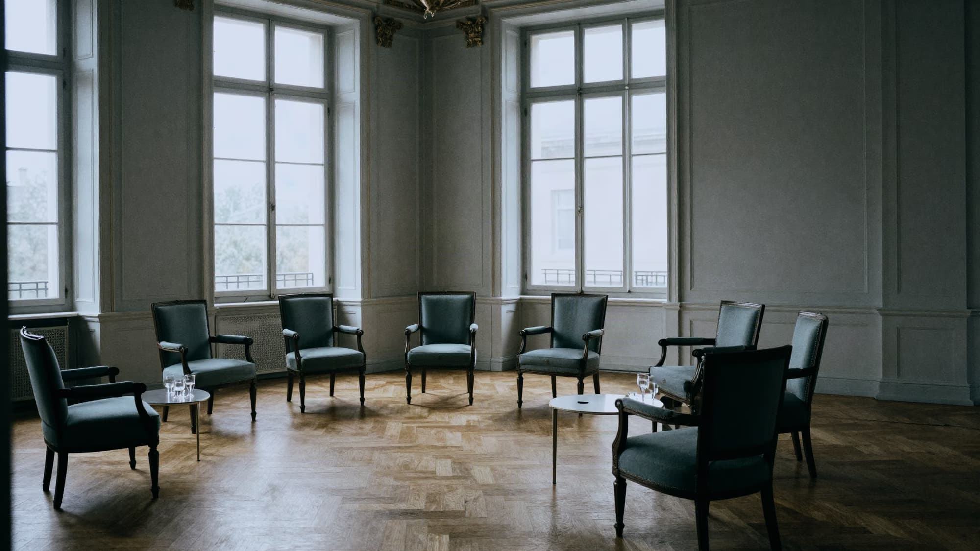 Salon d’honneur meublé de fauteuils disposés en demi-cercle, salle vide.